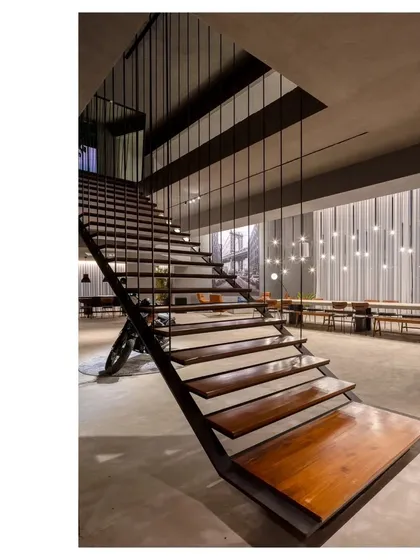 The staircase in the gallery space acts as a sculptural element, with its open design allowing views across the room. The combination of raw steel and warm wood is central to our material philosophy.