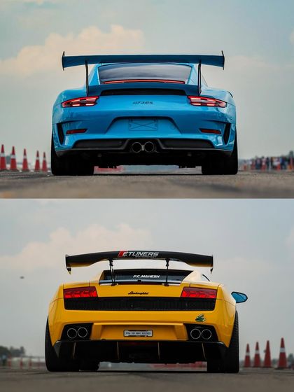 A side-by-side comparison of two track beasts: a blue Porsche GT3 RS and a yellow Lamborghini Gallardo. This is the kind of high-stakes supercar showdown you'll only witness at Vroom.