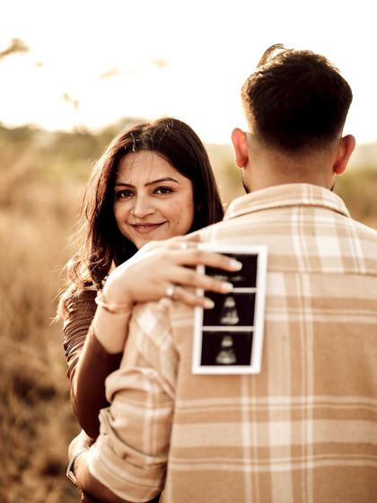 A beautiful over-the-shoulder shot with the sonogram on his back. Her loving gaze and the golden light make this a warm and intimate portrait.