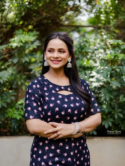 A confident and relaxed portrait. The actress stands with her arms crossed, smiling warmly, projecting an image of ease and self-assurance.