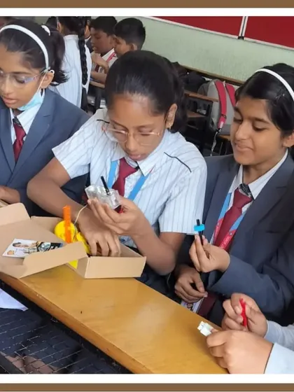 Three students collaborate on their project, examining the components from their kit. This image showcases the peer-to-peer learning and shared discovery that happens in our classrooms.