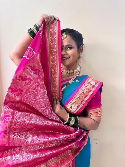 A shy and graceful pose, capturing the traditional essence of a Marathi bride. The vibrant pink and blue saree looks stunning with the soft makeup.