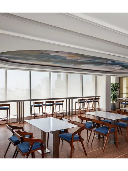 The dining area at the IHCL office offers stunning city views from its high-top counter seating. The space provides a variety of seating options, from large tables to this window-facing bar, catering to different preferences.