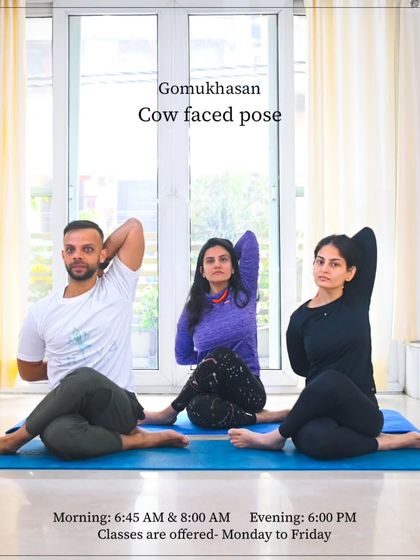 This photo from one of our classes shows me with students in Gomukhasana (Cow Faced Pose). It also includes our class timings, inviting new members to join our morning or evening sessions.