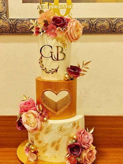 A cake as timeless as their love. I created this elegant three-tier white and gold cake to celebrate my parents' 50th anniversary, adorned with delicate flowers to represent their beautiful journey.