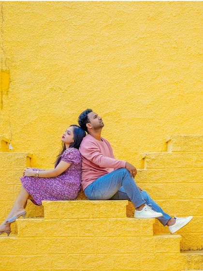 A striking and colorful shot of a couple sitting back-to-back on bright yellow steps.