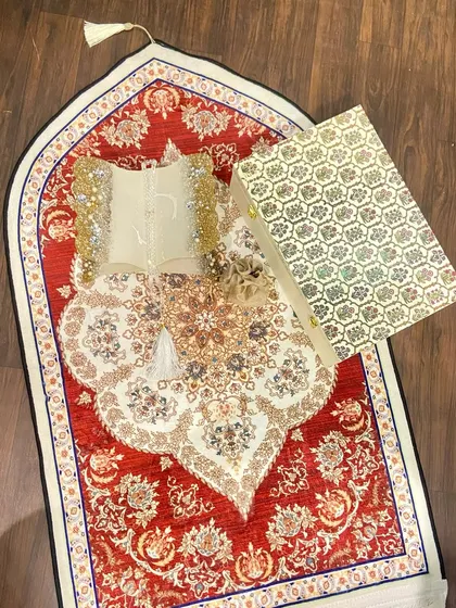 A beautiful Ramadan gift set featuring a dome-shaped prayer mat with an intricate red and white design. The set includes a custom Quran holder and a crystal tasbeeh, making it a perfect gift for the holy month.