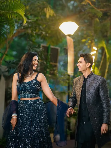 A joyful, candid moment as the couple walks hand-in-hand, sharing a laugh. This photo captures the fun and easy chemistry between them, set against a beautifully lit evening backdrop.
