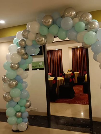 A stylish balloon arch in pastel blue, green, and silver, welcoming guests to a 4th birthday party.