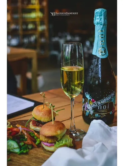 Sparkling wine served with mini burger sliders in a restaurant setting. This photo captures the dining experience, showing how beverages can be paired with food for promotional use.