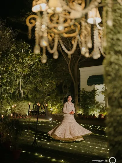 A dreamy, wide-angle shot of the bride enjoying her sangeet night. Her glowing makeup and elegant outfit make her the center of attention.