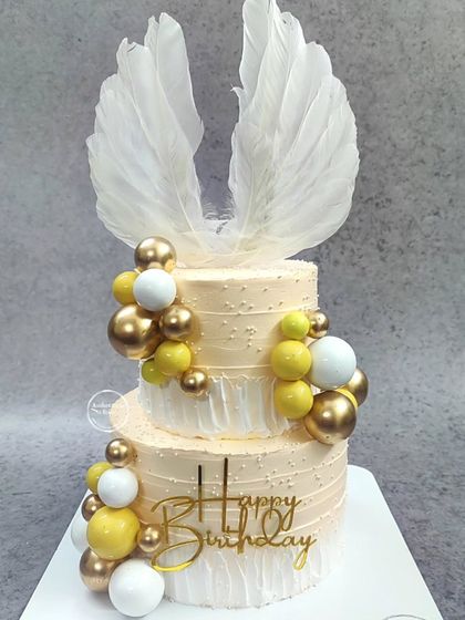 A grand two-tiered angelic birthday cake with large white feather wings.