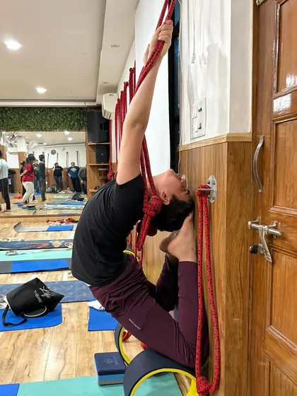 Advanced poses like this deep backbend become accessible with the right tools and guidance. We use wall ropes and a yoga wheel to support the spine, allowing you to open your heart and build flexibility with confidence.