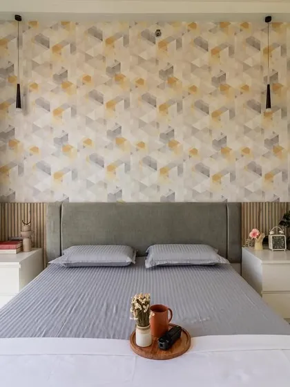 A full view of the bedroom with geometric wallpaper, showing the balanced composition with matching bedside tables and hanging pendant lights.