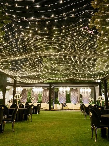 An elegant outdoor Sangeet with a canopy of fairy lights creating a magical, starry sky. The black and white theme with gold accents adds a touch of timeless Hollywood glamour.