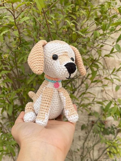 Here you can see the little tail and the posture of the handmade crochet dog. It's a small, palm-sized friend that can sit on a desk or shelf.