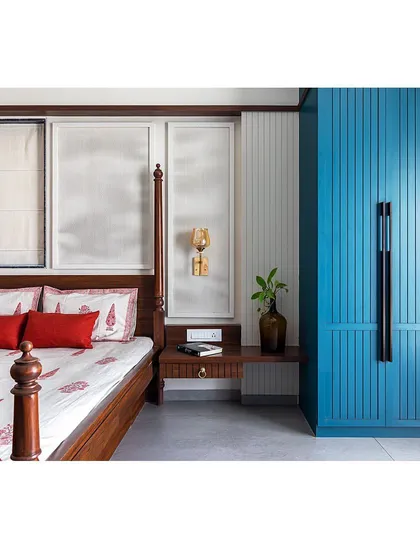 This shot highlights the contrast between the dark wood bed frame, the bold blue wardrobe, and the crisp white wall panels, creating a dynamic and visually balanced composition.