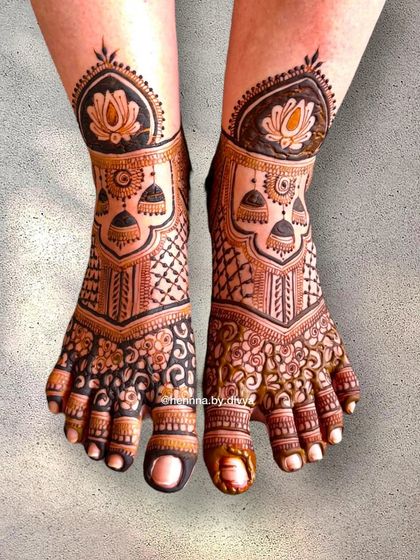 A rich and detailed design for bridal feet, extending up the leg. This piece features lotus motifs, hanging jhumkas, and intricate filler patterns.