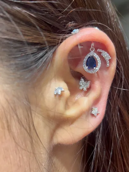 A deep blue sapphire-like stone in a teardrop shape, surrounded by a halo of smaller stones. This helix hanging adds a touch of royalty to the ear.