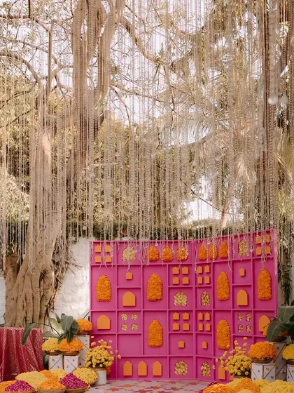 This Mehandi backdrop was all about making a statement. We designed a vibrant pink grid wall, filling it with bright orange and yellow marigold arrangements and adding a curtain of delicate hanging flowers for a touch of magic.