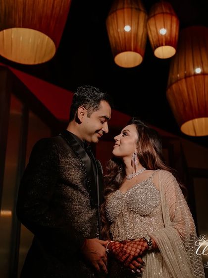 The couple shares an intimate glance under the warm, ambient lighting of their Sangeet venue.