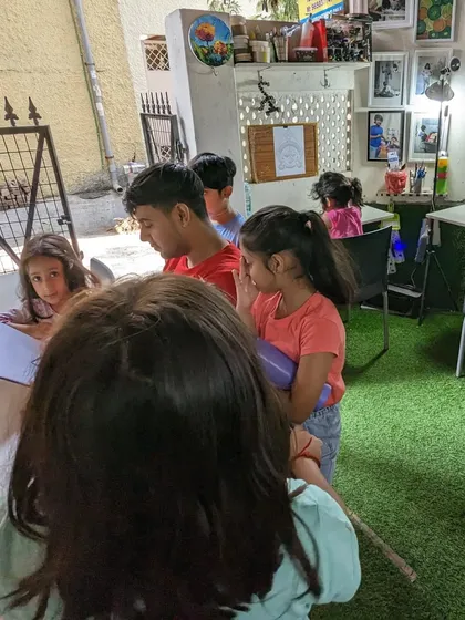 The students watch with curiosity and focus during a live drawing demonstration. These moments are key to their learning process.
