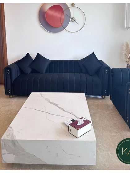 A frontal view of our navy blue channel-tufted sofa, paired with a solid white marble coffee table. The contrast between the dark, textured sofa and the smooth, light table creates a powerful design statement.