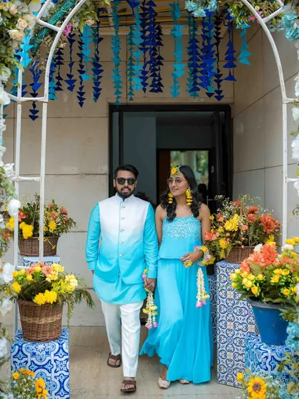 The couple's grand entrance at their Haldi ceremony. They look stylish and happy, ready to be celebrated by their loved ones. The floral decor adds to the festive atmosphere.
