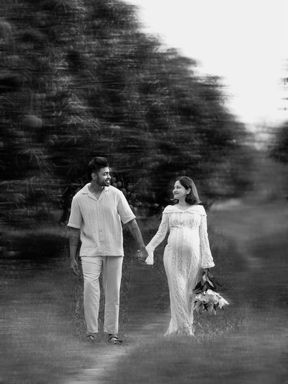 A black and white artistic shot of a couple walking together during their outdoor maternity session, creating a sense of movement and story.