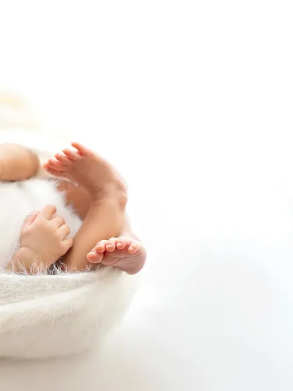 A minimalist shot focusing on the baby's tiny hands and feet as they curl up. The white space makes the subject feel so delicate.