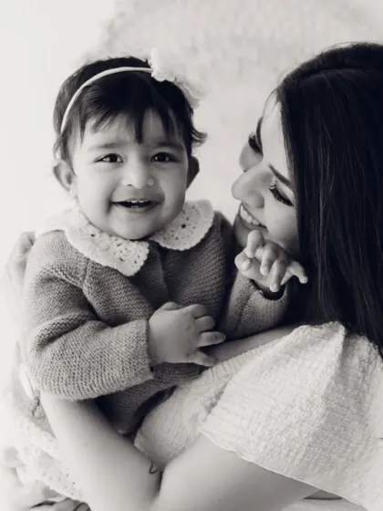 A mother and her baby share a smile in this lovely black and white portrait. The soft lighting creates a gentle and intimate feel.