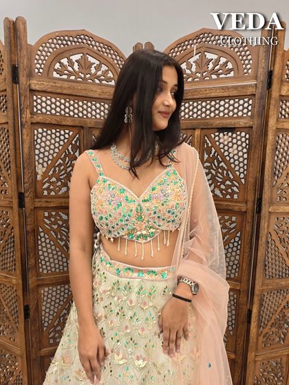 A close-up of the pastel green lehenga's blouse, showing the vibrant and cheerful floral embroidery.