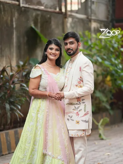 A happy couple at their engagement, with the groom wearing a custom-designed Indo-Western sherwani. The nature-inspired embroidery adds a personal and artistic touch to his ceremonial attire.