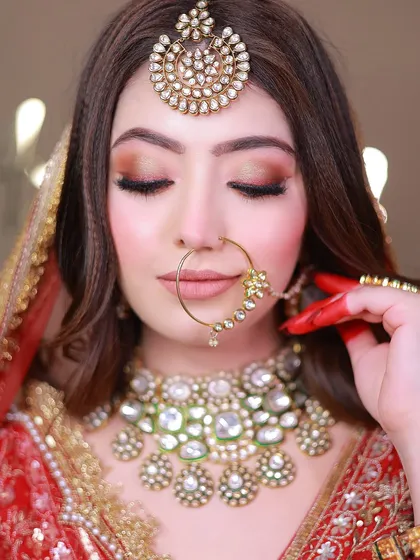 An extreme close-up on the bride's face, highlighting the flawless makeup, maang tikka, and nose ring.