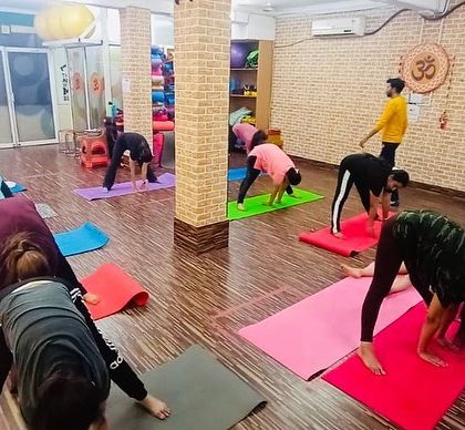 The class is engaged in a deep forward bend, a key part of our flexibility improvement yoga. I am present to offer support and adjustments.