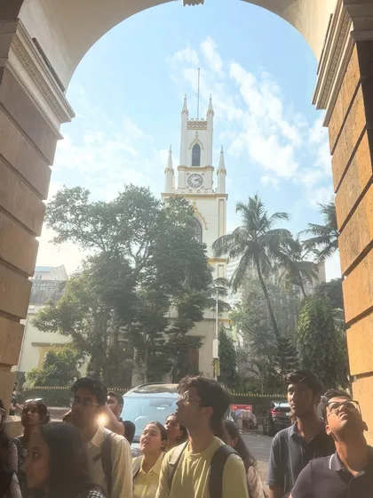 A group of students looks up at a historic clock tower in Mumbai during a site visit. Our workshops always include site adventures to connect theoretical learning with the tangible experience of the built environment.