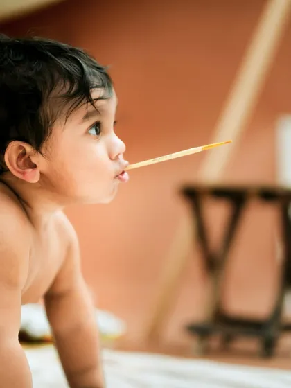 A tiny artist in thought. This creative milestone session captures the curiosity of a baby exploring new things, like a paintbrush.