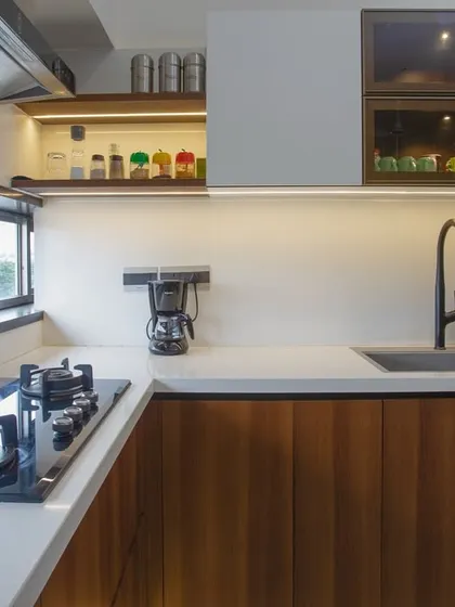 Every detail is considered for function. The matte black faucet is a modern counterpoint to the warm wood, and the open shelving next to the hob keeps spices and oils within easy reach for the active cook.