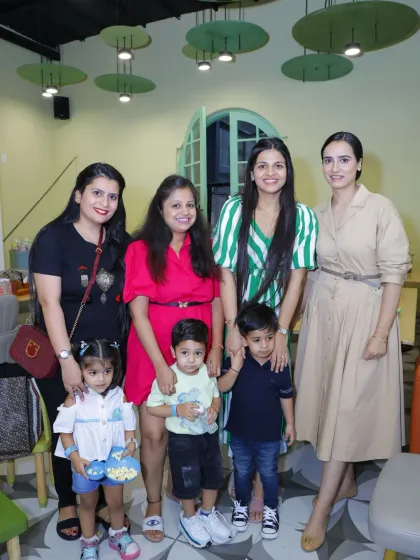 A group of friends and their children gather for a happy photo during a party.