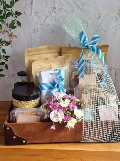 A large hamper for Dad, featuring a faux leather tray filled with snacks and a fresh flower arrangement.