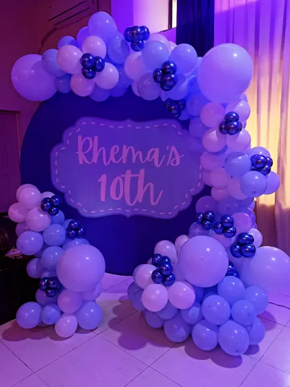 A lovely purple and white themed decoration for a 10th birthday. The circular backdrop with a custom nameplate is framed by a beautiful balloon arrangement.