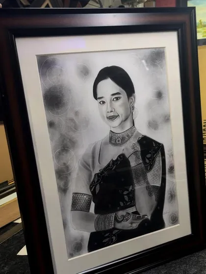 Another angle of the framed realistic portrait, showing how the dark wood frame complements the black and white artwork.