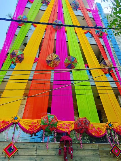 Another angle of the vibrant house front, showing the density and arrangement of the colourful drapes and decorative umbrellas.