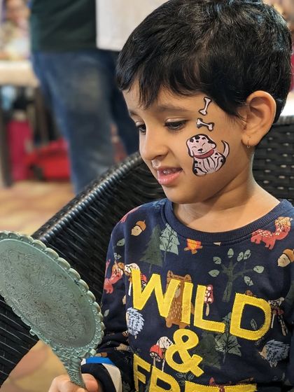 The magical moment when a child sees their face paint for the first time. This boy is delighted with his puppy and bones design.