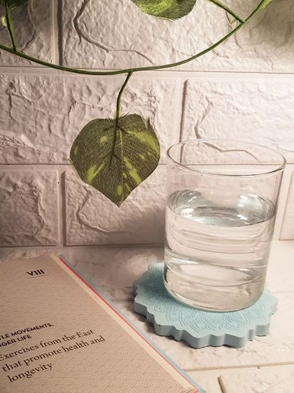 The icy blue Mandala coaster in use, protecting a surface from a glass of water. It’s a perfect example of functional beauty.