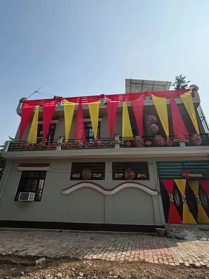 A simple yet festive decoration for a smaller house. The balcony and gate are decorated with red and yellow drapes, instantly signaling a celebration.