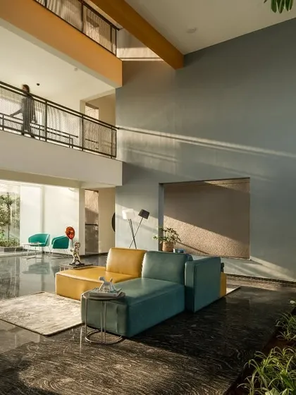The double-height entrance lobby of 'The Treehouse' apartments is designed to maximize natural light and create a welcoming, open atmosphere. We integrated lush indoor planting and contemporary furniture to blur the line between the interior and the surrounding landscape, establishing a serene arrival experience for residents.