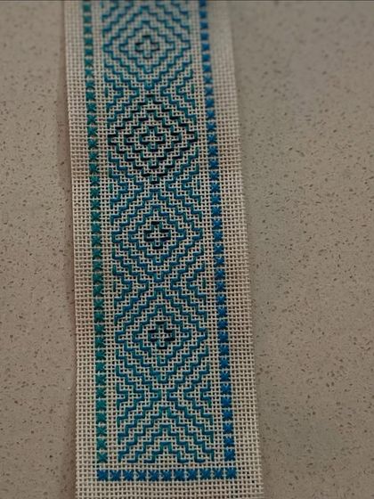 A Kasuti bookmark featuring a gradient effect created by using different shades of blue thread. This demonstrates how color choice can add another layer of artistry to the craft.