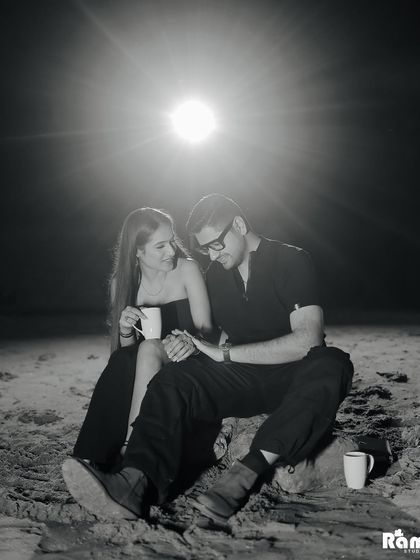 A cozy and candid black and white moment from a campfire scene. Sharing a cup of chai under the moonlight, this image feels authentic and heartwarming.