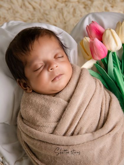 A classic and clean setup with a neutrally wrapped baby and a bouquet of tulips, adding a fresh, gentle touch of color.
